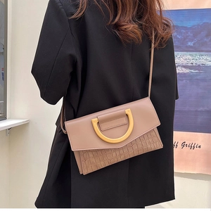 Detail of brown crocodile pattern shoulder bag with a gold D-ring buckle