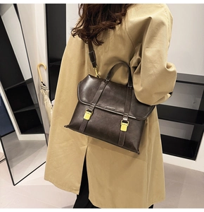 Close-up of vintage dark brown faux leather bag with gold buckle on trench coat model