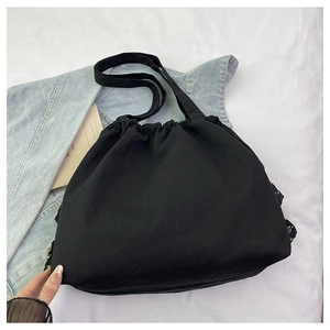 Detalle de un bolso tote negro con volantes y cierre de cordón en un ambiente de estilo de vida