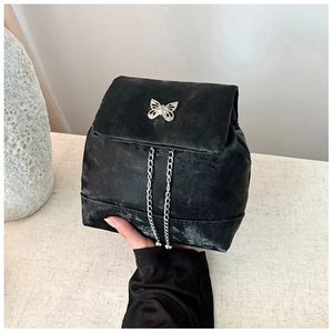 Detailed macro shot of a black mini backpack with silver butterfly and chain accents