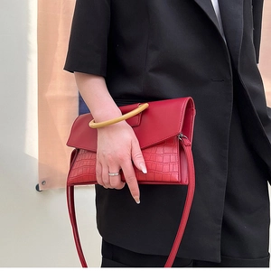 Detail of red crocodile texture handbag with unique round resin handle and black blazer