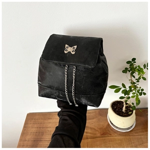 Close-up of black velvet mini backpack with silver butterfly buckle and long chains