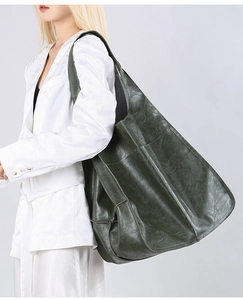 Dark green oversized tote bag in vintage textured leather styled on a white blazer