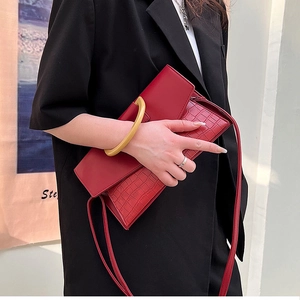 Close-up of red crocodile pattern handbag with yellow ring handle and thin strap