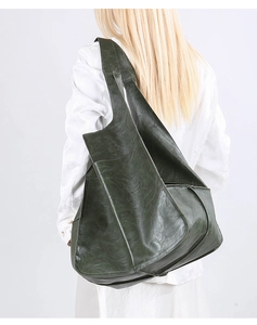 Detailed view of the vintage wrinkled texture on the dark green leather tote bag