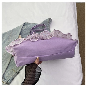 Detalle del bolso tote de lona morada con ribete de volantes florales sobre denim azul