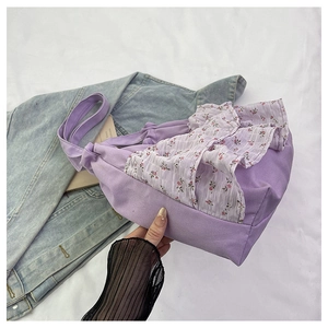 Detalle de bolso tote de lona lavanda con adornos de volantes florales sobre fondo denim