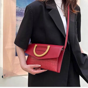 Detail shot of a red crocodile embossed clutch bag with a golden semicircular metal buckle
