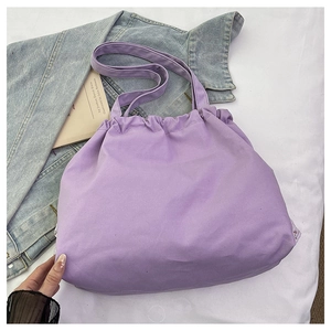 Primer plano del bolso tote de lona violeta claro con cierre de cordón y correa larga