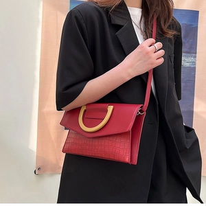 Detail of red crocodile texture crossbody bag with gold U-ring buckle on model