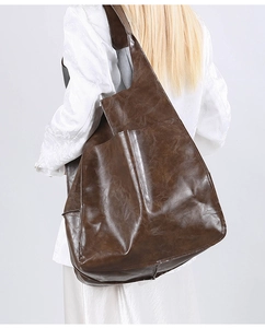 Brown vintage leather tote bag shown on shoulder, highlighting large capacity and soft texture