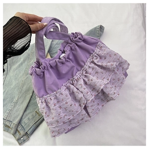 Detalle del diseño de volantes florales y textura de lona púrpura en este bolso