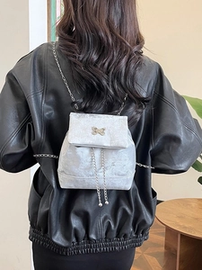 Silver velvet mini backpack with metal butterfly hardware and chain straps on person