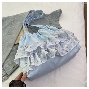 Detalle de los volantes florales y cierre de cordón en el bolso de lona azul claro