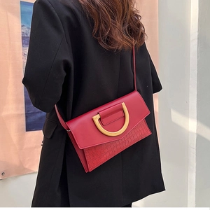 Detail of red crocodile texture handbag with golden D-ring buckle on a fashion model
