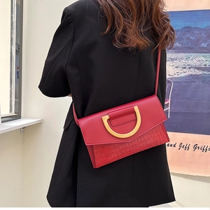 Detail of red crocodile texture crossbody bag with gold buckle on black blazer