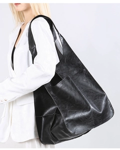 Side view of black large capacity tote bag with front pocket shown on model