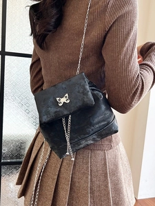 Mini black backpack with silver bow hardware and chain tassel on a model back