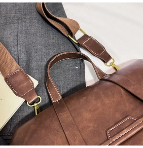 Detailed close-up of brown vintage leather bag with stitching and bronze hardware