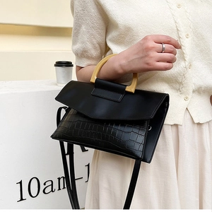 Detail of elegant black crocodile pattern handbag with a unique yellow resin handle