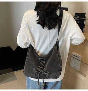 Sac bandoulière en denim gris foncé avec nœud et cordon porté par un mannequin