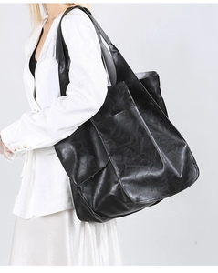 Detail view of black vintage tote bag side pocket with matte leather texture on a model