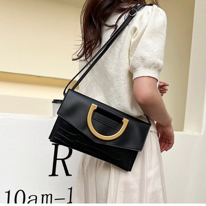 Detailed view of black crocodile pattern bag with gold D-ring buckle on a model
