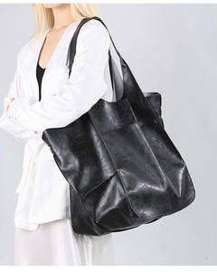 Detail of a black large-capacity leather tote bag with soft texture and side pocket