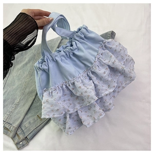 Detalle de bolso tote de tela azul claro con volantes florales blancos de doble capa