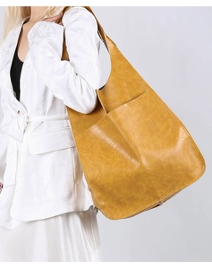 Detailed close-up of a large vintage yellow leather tote bag worn over the shoulder