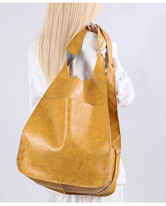 Detail of a large mustard yellow PU leather tote bag with soft texture and wide shoulder strap