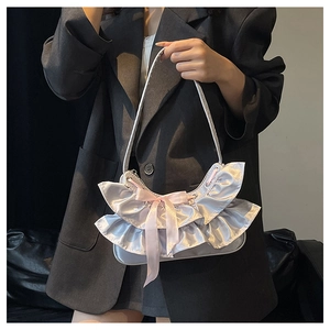 Close-up of a silver ruffled shoulder bag featuring a pink satin bow and mesh stitching