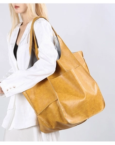Close-up of ginger yellow large capacity tote bag with soft leather texture on a model