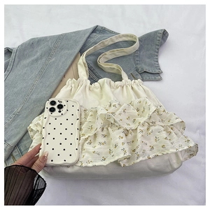 Detalle de volantes y motivos florales amarillos en un bolso de lona color crema