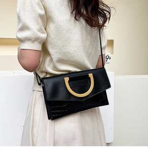 Fashionable black faux crocodile skin shoulder bag worn by model in a white studio setting