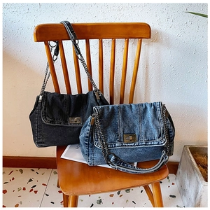 Nahaufnahme der Vintage-Jeans-Handtasche mit bronzener Metallkette auf Holzstuhl