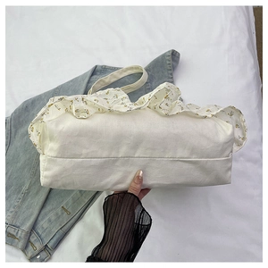 Detalle de bolsa tote de lona blanca con ribete de volantes y estampado floral amarillo