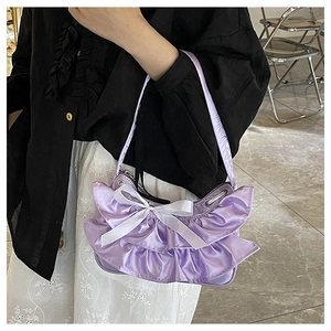 Detail view of purple pleated underarm bag featuring a large white satin bow accent