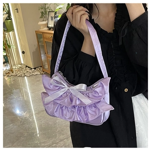 Close-up of lilac ruffled satin handbag with a white ribbon bow and layered textures