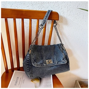 Detail der gewaschenen blauen Denim-Umhängetasche mit silbernem Drehschloss und Kettenriemen