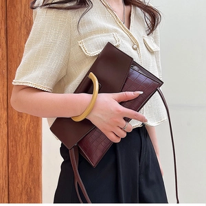Detail of elegant two-tone clutch featuring crocodile texture and yellow semi-circle handle