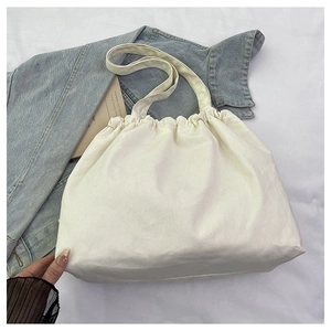 Detalle del bolso tote de lona marfil con apertura plisada tipo nube y correas resistentes