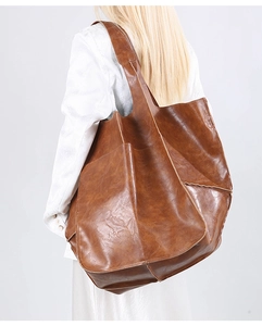 Side view of oversized brown soft leather tote bag showing large capacity and rich texture