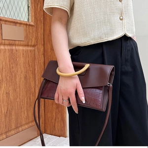 Detail of dark brown faux-crocodile handbag featuring unique round wooden handle