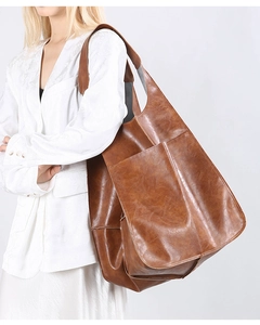 Close-up of a large brown leather tote bag with external pocket on a model