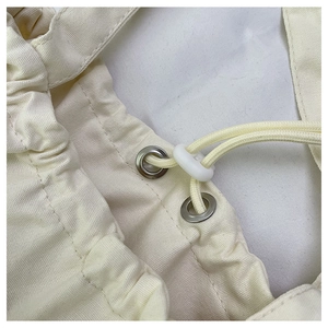 Detalle de tela de lona gruesa con ojales metálicos y cierre de cordón ajustable de color beige