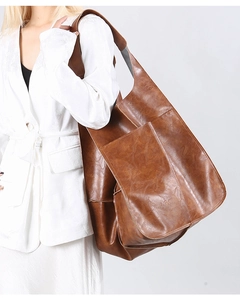 Detail view of large brown vintage tote bag showing soft leather texture and side pocket