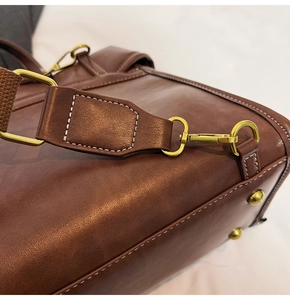 Detail of vintage brown leather bag showing brass hardware and contrast stitching