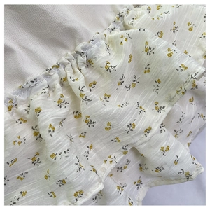 Detalle de la textura del tejido seersucker con estampado floral amarillo y volantes