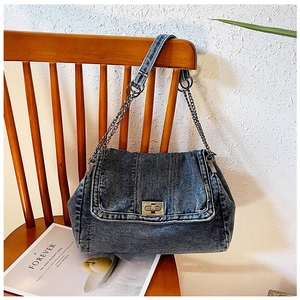 Detail der blauen Jeans-Umhängetasche mit Metalldrehverschluss und silbernem Kettenriemen